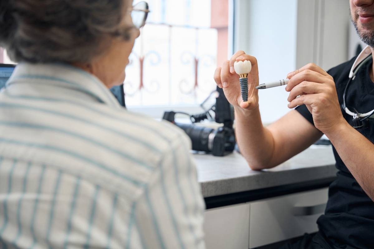 Specialist demonstrates a model of a dental implant to a patient.